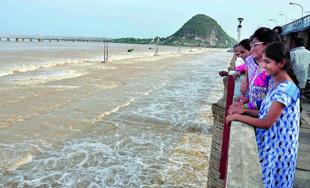 Youth watch water gushing out from Prakasam Barrage in Vijayawada on Monday. (Photo: DC) Youth watch water gushing out from Prakasam Barrage in Vijayawada on Monday. (Photo: DC)